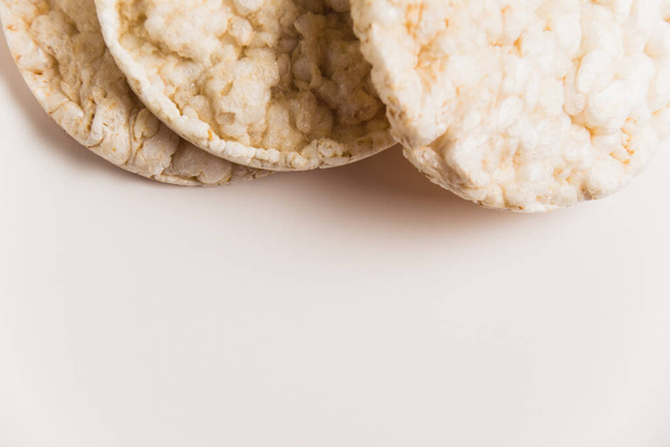 Νόστιμο τραγανό διογκωμένο ρύζι ψωμάκια σε λευκό φόντο με χώρο αντίγραφο. Διατροφή και υγιεινή διατροφή έννοια - Φωτογραφία, εικόνα