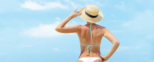 Parte posterior de la hermosa chica en bikini en la playa frente al cielo soleado. Disfrute y relájese en verano con espacio para copiar - Foto, imagen