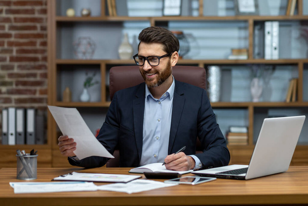 Mature successful financier working inside office at workplace with contracts and papers businessman behind paper work reading financial report, experienced analyst satisfied with achievement results - Fotoğraf, Görsel