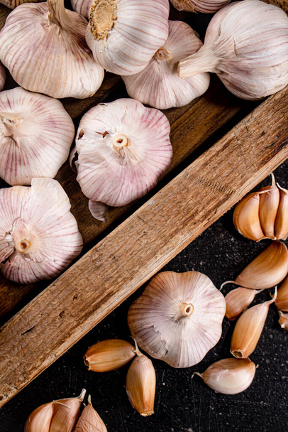 Heads and cloves of fresh garlic. On a black background. High quality photo - Φωτογραφία, εικόνα