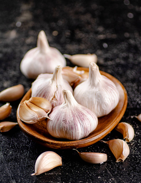 Fresh garlic on a wooden plate. On a black background. High quality photo - Fotoğraf, Görsel