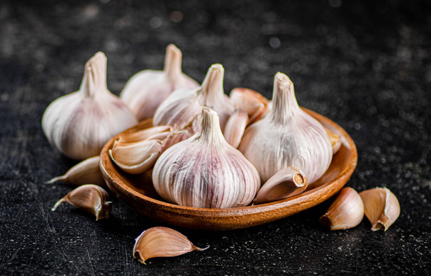 Fresh garlic on a wooden plate. On a black background. High quality photo - Foto, imagen