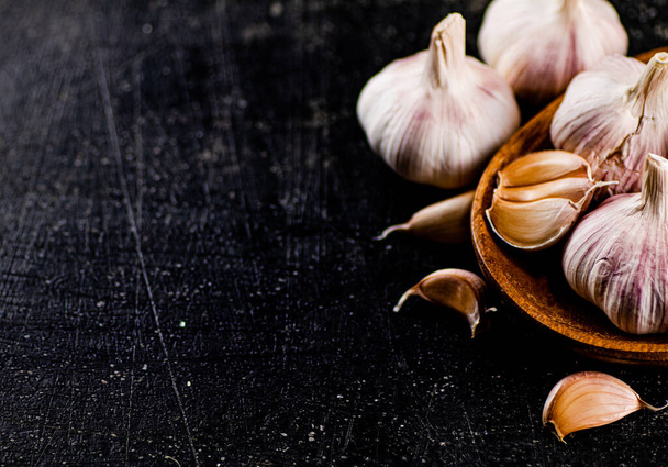Fresh garlic on a wooden plate. On a black background. High quality photo - Valokuva, kuva