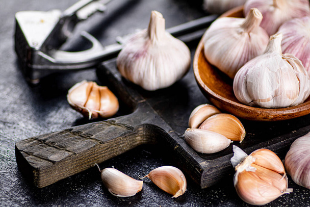 Garlic on a wooden plate on a cutting board. On a black background. High quality photo - Photo, image
