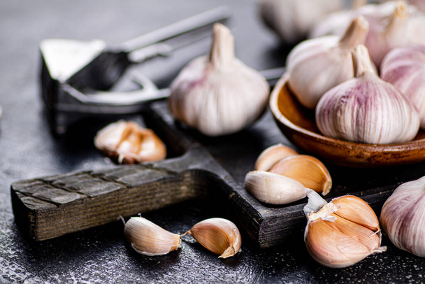 Garlic on a wooden plate on a cutting board. On a black background. High quality photo - Foto, Bild