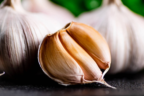Fragrant garlic with parsley on the table. On a black background. High quality photo - Foto, immagini