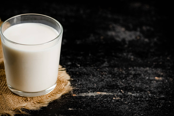 A full glass of fresh milk on a napkin. On a black background. High quality photo - Foto, immagini