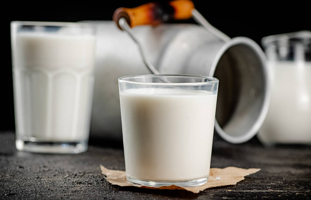 Fresh country milk in a glass on the table. On a black background. High quality photo - Fotó, kép