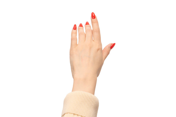 Primo piano della mano femminile con pelle pallida e unghie rosse che puntano o toccano isolato su uno sfondo bianco.  - Foto, immagini