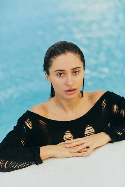 atractiva joven con piel bronceada en traje de baño negro en la piscina pública, posando y disfrutando de sus vacaciones de verano en un resort de lujo en Miami, sin maquillaje, escapada de verano, retrato  - Foto, imagen