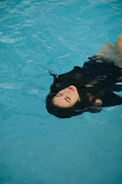 letni wypad, beztroska kobieta w czarnych strojach kąpielowych relaksująca się podczas kąpieli w publicznym basenie w luksusowym kurorcie w Miami, lśniąca woda, wolność, orzeźwiająca, ośrodek w Miami  - Zdjęcie, obraz