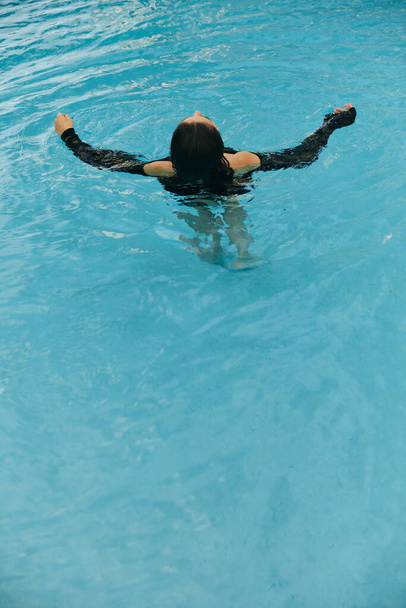 "Літні ворота", "безтурботна жінка, що плаває в блакитній воді громадського басейну в розкішному курорті в Маямі, мерехтлива вода, свобода, релаксація, курорт в Маямі.  - Фото, зображення