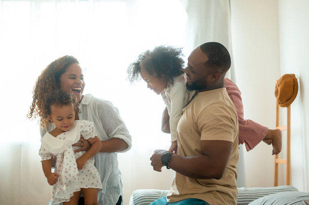 Happy African American Parents with  little daughters playing on the bed in bedroom at home, happy family concept - Valokuva, kuva