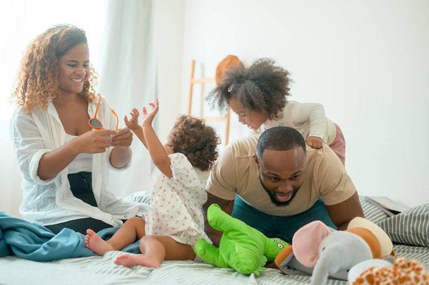Happy African American Vanhemmat pienet tyttäret leikkivät sängyllä makuuhuoneessa kotona, onnellinen perhekonsepti - Valokuva, kuva