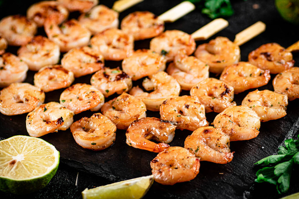 Grilled shrimp on a stone board with parsley and lime. On a black background. High quality photo - Photo, image