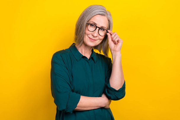 Portrait of successful smart aged lady arm touch eyeglasses isolated on yellow color background. - Foto, immagini