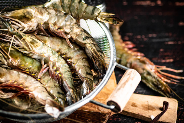 Fresh uncooked shrimp in a colander. On rustic dark background. High quality photo - 写真・画像