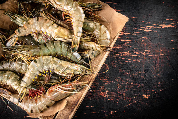 Raw shrimp on a wooden tray. Against a dark background. High quality photo - Foto, afbeelding