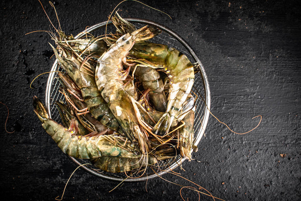 Fresh raw shrimp in a colander. On a black background. High quality photo - Zdjęcie, obraz