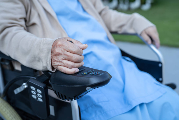 Asiatique femme âgée patient sur fauteuil roulant électrique avec joystick et télécommande à l'hôpital. - Photo, image