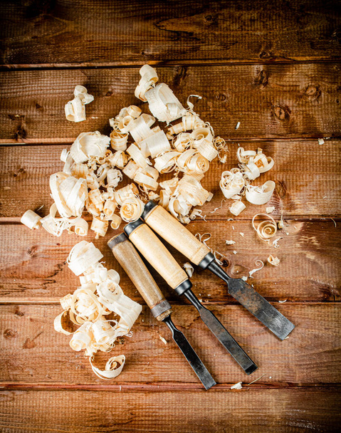 Chisel with a bunch of wood sawdust. On a wooden background. High quality photo - Photo, Image