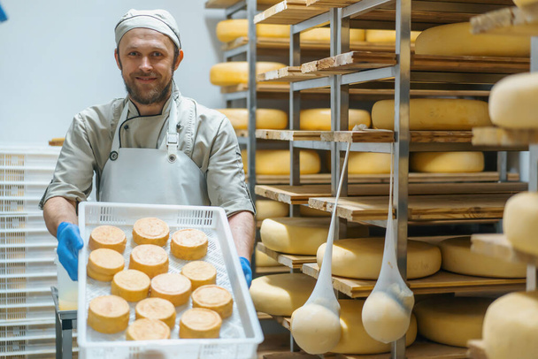Улыбающиеся сыроделы держат в ящике свежий сыр на молочном складе Молочное производство Успешный сельскохозяйственный бизнес - Фото, изображение