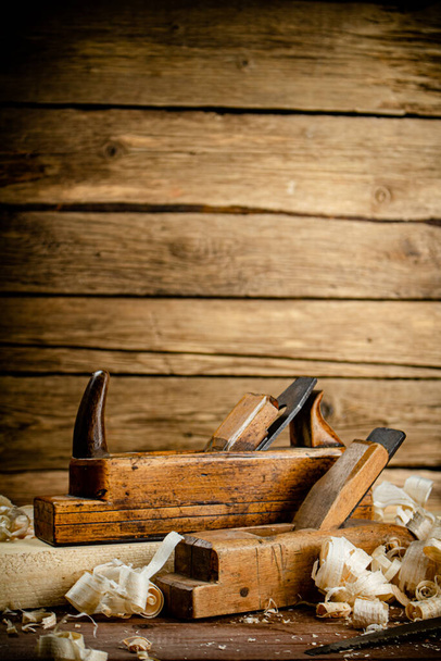 Working tool. Planer with wooden shavings. On a wooden background. High quality photo - Fotografie, Obrázek
