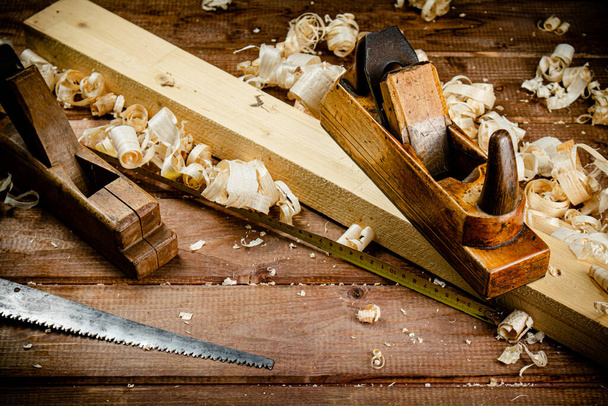 Working tool. Planer with wooden shavings. On a wooden background. High quality photo - Fotoğraf, Görsel