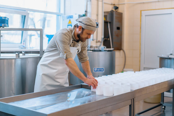Käsemacher in Uniform macht Käse stellt Formen zum Gießen Käse Produktionsprozess Kleinunternehmen und Unternehmertum - Foto, Bild