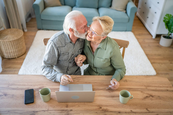 カップル成熟したシニア女性と男の夫と妻は自宅で座っているオンラインショッピングのクレジットカードやデビットカードを使用してネットショップを参照してください物事を購入するラップトップコンピュータを使用して実際の人々コピースペース - 写真・画像