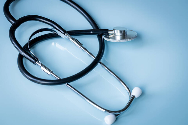 medische stethoscoop liggend op een pastelblauw glazen bureau, concept van gezondheid, geneeskunde en medisch onderzoek - Foto, afbeelding