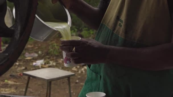 Een close-up van geëxtraheerd suikerrietsap wordt geserveerd in wegwerpbekers. Bedrijfsconcept. Het levensstijl concept van arme mensen - Video