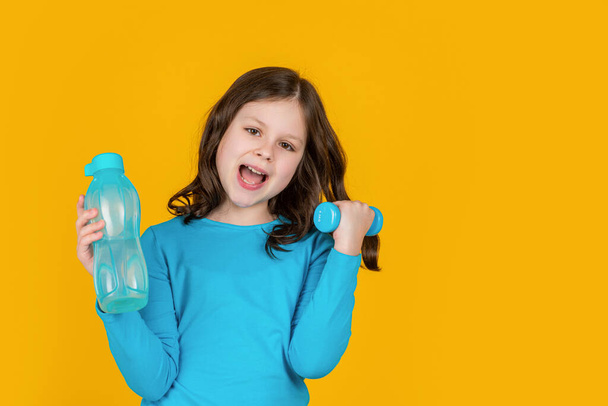 happy child with barbell and sport bottle on yellow background. - Foto, Bild