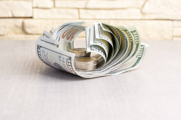billets de banque de dollars et de pièces torsadés sur une table grise, gros plan, vue de face. - Photo, image