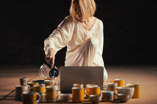 Deadline, recycling concept. Woman and many coffee cups in front of a laptop. A dark room. - Zdjęcie, obraz