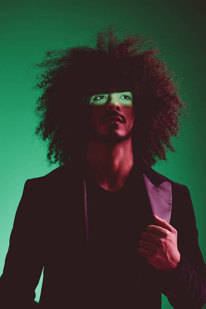 Portret stylowego mężczyzny w kurtce na zielonym tle wielonarodowe, kolorowe światło, trend. Wysokiej jakości zdjęcie - Zdjęcie, obraz