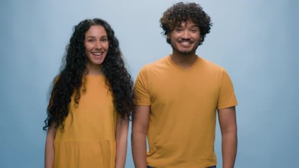 Diverse multiracial couple different opinions answers smiling together woman answer no negative Indian Arabian man agree nod yes isolated at blue studio background disagree discrepancy nonconformity - Footage, Video