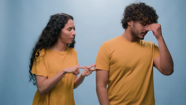 Multiracial couple family quarrel Arabian Indian man husband ignoring wife cover ears with hands refuses listen argue angry Hispanic woman conflict problem bad relationship in blue studio background - Footage, Video