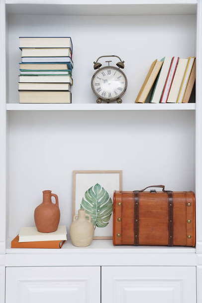 Books and different decorative elements on shelving unit indoors - Photo, image