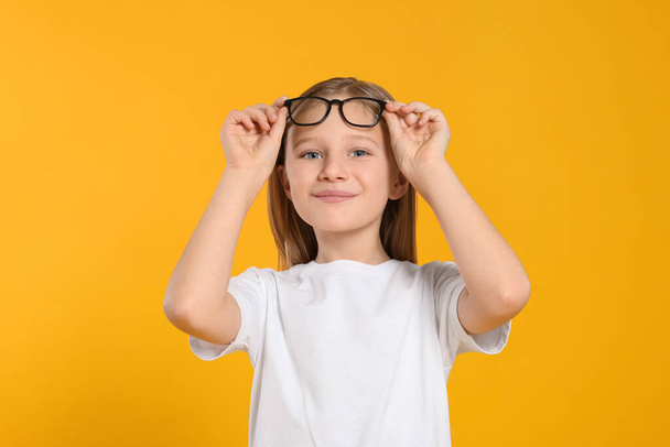 Portrait of cute girl with glasses on orange background - Photo, image