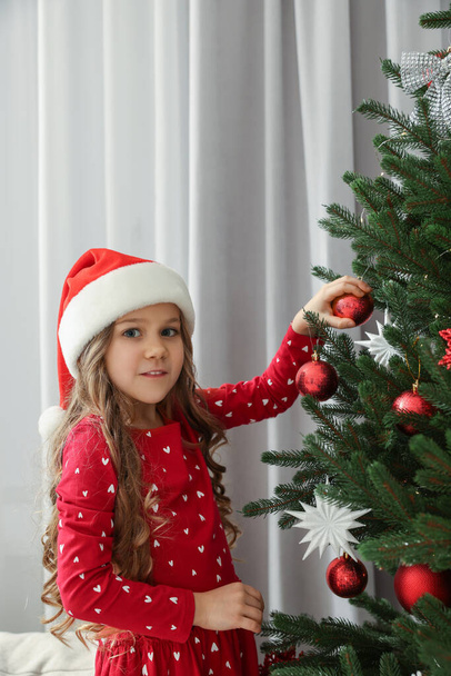 Happy little girl decorating Christmas tree at home - 写真・画像