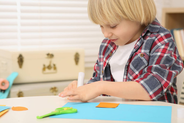 Boy using glue stick at desk in room, closeup. Home workplace - Foto, immagini