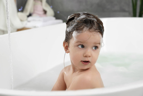 Cute little girl washing hair with shampoo in bathroom - Photo, image