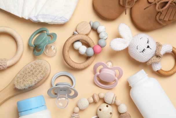 Flat lay composition with pacifiers and other baby stuff on beige background - Foto, afbeelding