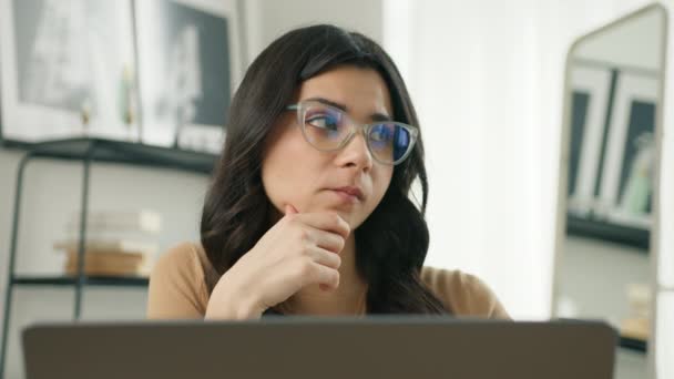Znepokojená latinoameričanka v brýlích pracující na notebooku, odvracející se od přemýšlení o vyřešení problému v domácí kanceláři. Zblízka seriózní žena hledá inspiraci, rozhodování nedostatek nápadů 4K - Záběry, video