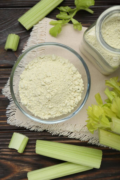 Natural celery powder and fresh stalks on wooden table, flat lay - Foto, afbeelding