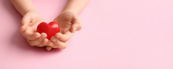 Gyermek kezét piros szív rózsaszín háttérrel helyet a szöveges - Fotó, kép