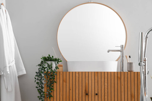 Wooden cabinet with sink bowl, faucet and mirror in interior of bathroom - Fotó, kép