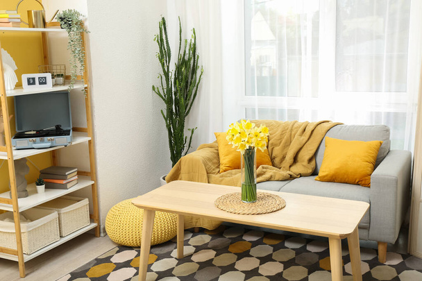 Interiér světlého obývacího pokoje s kvetoucími květy narcisu ve váze na stole - Fotografie, Obrázek