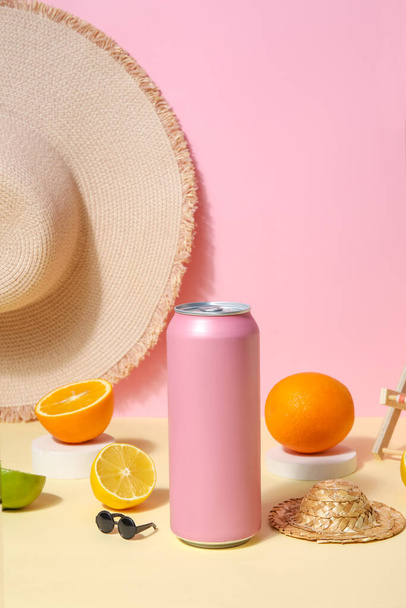 Can of soda with beach accessories and citrus fruits table near pink wall - Foto, Bild